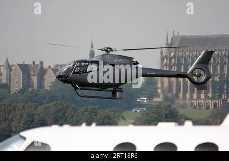 Ein Eurocopter EC 120B Colibri, der am Flughafen Brighton City ankommt, mit Lancing College im Heck und einem Cessna Business Jet im Vordergrund Stockfoto