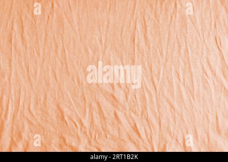 Zerknitterter, zerknitterter orangefarbener Texturhintergrund. Zerknitterte und geknitterte abstrakte Kulisse aus Baumwolljersey-Textil, Tapete mit Kopierraum, Top V Stockfoto