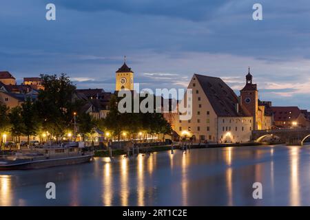 Rathausturm von Regensburg und Salzstadel am Ufer der Donau mit Steinbrücke bei Nacht Stockfoto