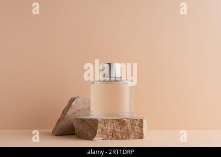 Mockup-Steinpodium mit Glasparfumflasche auf beigem Hintergrund Stockfoto