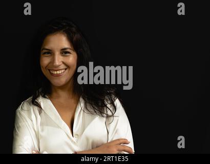 lateinische Sekretärin mit weißem Hemd und schwarzem Hintergrund lächelnd Stockfoto