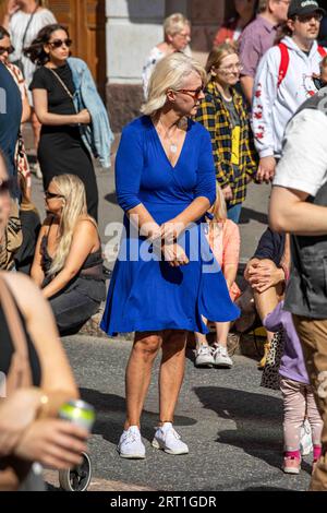 Frau mittleren Alters mit blauem Kleid, die an einem sonnigen Sommertag in Helsinki, Finnland, in der Menge steht Stockfoto