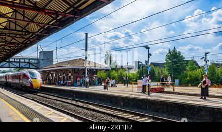 Ein LNER Azuma-Zug fährt an einem Sommertag unter einem blauen Sommerhimmel mit hoher Geschwindigkeit durch den Bahnhof Grantham Stockfoto