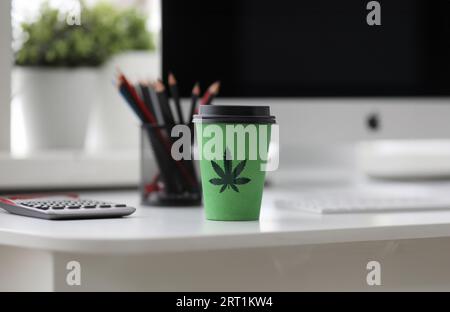 Grüner Kaffee Tasse mit Cannabis Logo auf Office Tabl Stockfoto