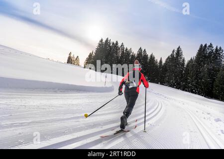 Hübsche aktive Seniorenläuferin im frisch gefallenen Pulverschnee in den Allgäuer Alpen bei Immenstadt, Bayern Stockfoto
