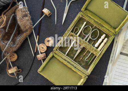 Antike seltene Nähgarderei in offener grüner Samtbox mit Schere, Nähnadeln und Häkelhaken aus Metall und Tierknochen in sehr gutem Zustand Stockfoto