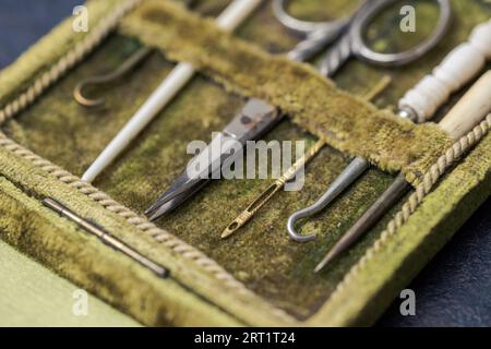 Detail von antikem seltenen Nähset in offener grüner Samtbox mit Schere, Nähnadeln und Häkelhaken aus Metall und Tierknochen in sehr guter Form Stockfoto