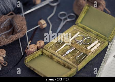 Antike seltene Nähgarderei in offener grüner Samtbox mit Schere, Nähnadeln und Häkelhaken aus Metall und Tierknochen in sehr gutem Zustand Stockfoto