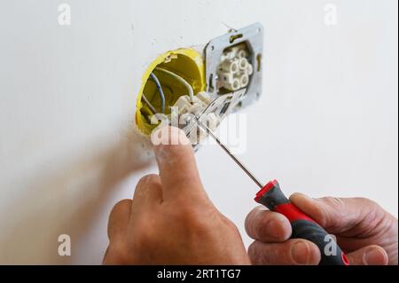 Ein Elektriker installiert eine Steckdose in die Wand. Nahaufnahme. Stockfoto