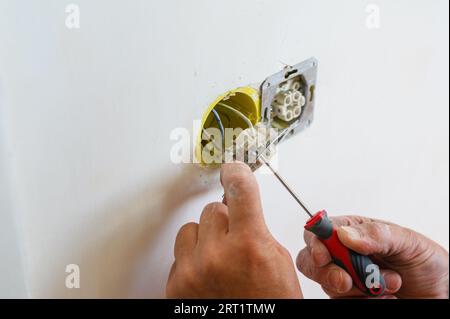 Ein Elektriker installiert eine Steckdose in die Wand. Nahaufnahme. Stockfoto