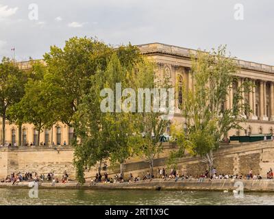 Menschen sitzen und entspannen am Ufer der seine, Nr Louvre Museum, Ägyptische Gegend, Paris, Frankreich, Europa, EU. Stockfoto