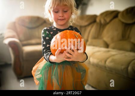 Die junge Hexe hält einen verzauberten Kürbis und macht sich bereit für Halloween. Stockfoto