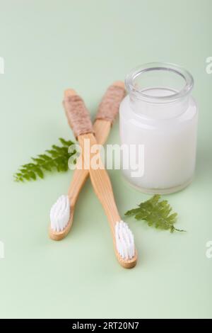 Natürliche Bambuszahnbürsten und Kokosnusszahnpasta auf grünem Hintergrund, Zero Waste Produkte, natürliche Mundhygiene Stockfoto