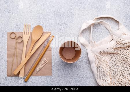 Zero Waste Bambus Geschirr, umweltfreundliche Papierbecher und Serviette, Stroh, Tasche, Holzbesteck auf Naturstein Hintergrund. Kopierbereich von oben Stockfoto