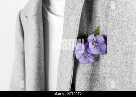 Graue Jacke und weiße Hemden auf dem Gestell, Blume in der Tasche Stockfoto