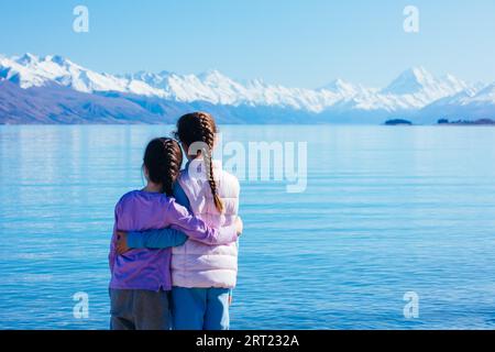 Kleine Kinder blicken an einem kristallklaren Frühlingsmorgen in Neuseeland auf den Mt Cook und den Lake Pukaki Stockfoto