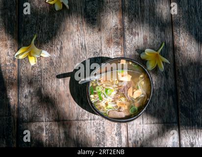 Soto Batok, eine traditionelle javanische Rindersuppe mit Gemüse und Reis, serviert in einer traditionellen Schüssel aus Kokosnussschale. Stockfoto