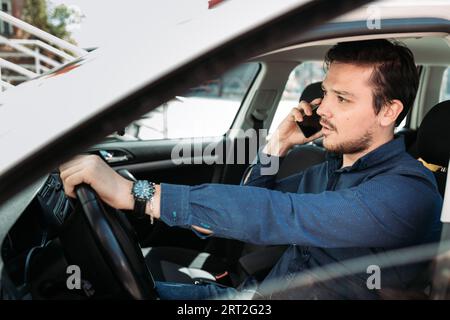 Junger Mann, der in seinem Auto telefoniert Stockfoto