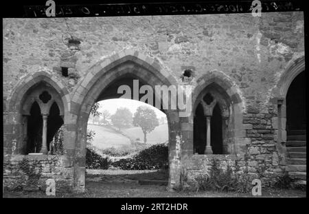 Cleeve Abbey, Chapter House, Old Cleeve, West Somerset, Somerset, 1940-1948. Eine Außenansicht des Kapitelhauses in der Abtei von Cleeve, vom Kreuzgang aus gesehen. Eine Außenansicht des Kapitelhauses in der Abtei von Cleeve, vom Kreuzgang aus gesehen. Das Bild zeigt den Eingang zum Kapitelhaus und die zwei-Licht-Fenster auf beiden Seiten. Auf der rechten Seite befindet sich eine Teilansicht einer Innentreppe. Der Hintergrund ist durch das Kapitelhaus deutlich sichtbar, und was als Ruine der Ostwand erscheint, befindet sich in der Mitte. Stockfoto