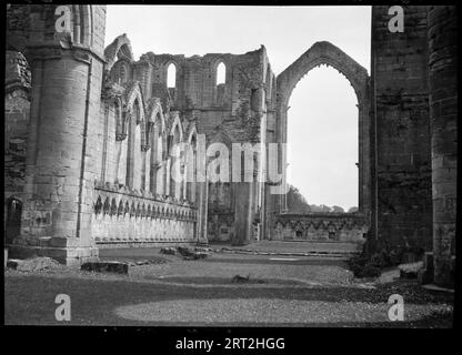 Fountains Abbey, Harrogate, North Yorkshire, 1940-1949. Ein Blick auf das östliche Ende des Kirchenschiffs, aus dem Inneren der Ruinen des Kirchenschiffs. Der Fotograf scheint ganz rechts auf der Südseite des Kirchenschiffs zu stehen, und die mit Dreiflossen versehenen Vertiefungen auf der Nordseite sind deutlich sichtbar. Die Abtei wurde 1132 von Zisterziensermönchen gegründet und die Hauptbauzeiten fanden zwischen 1170-1247 und dem späten 15. Jahrhundert bis zum frühen 16. Jahrhundert statt. Die Abtei war nach der Auflösung im Besitz vieler Menschen und befindet sich derzeit im Besitz des National Trust. Stockfoto