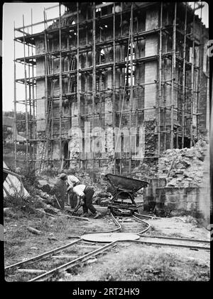 Rievaulx Abbey, Rievaulx, Ryedale, North Yorkshire, 1924-1929. Das Refektorium in der Rievaulx Abbey wird restauriert, mit Gerüsten rund um das Gelände, einer temporären Eisenbahn für den Transport von Baumaterial und Schutt und zwei Männern, die im Vordergrund arbeiten. Die Sanierung und Räumung des Geländes erfolgte in den 1920er Jahren Stockfoto