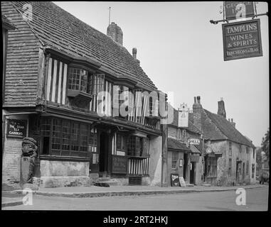 Das Star Inn, High Street, Alfriston, Wealden, East Sussex, 1940-1949. Eine Straßenansicht der High Street in Alfriston mit Schwerpunkt auf dem Star Inn, auf der linken Seite des Bildes. Das inn ist ein Fachwerkgebäude aus dem 15. Jahrhundert mit Gipseinfüllung und einem überdachten Obergeschoss mit drei Fenstern. Ganz links befindet sich ein Pfosten mit einer Tierschnitzerei. Rechts vom inn befinden sich zwei weitere denkmalgeschützte Gebäude: Das erste ist das Saddler's House und das YE Olde Tea House, das Schilder an das Gebäude anlehnt und ein Hängeschild über der Tür hat, und das zweite, weiter im Hintergrund, ist Patricia Okel Stockfoto