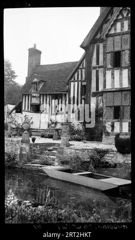 Huddington Court, Huddington, Wychavon, Worcestershire, 1940-1948. Ein Außenblick auf Huddington Court, mit einem Wasserkörper und einem gepflasterten Garten im Vordergrund. Auf dem Wasser liegt ein kleines Holzboot neben einer Treppe, die zum gepflasterten Garten und zum Haus führt. Das Bild zeigt möglicherweise die Ostseite des Hauses, wobei der Wasserkörper Teil des Grabens ist, der das Anwesen umgibt. Huddington Court ist ein Haus aus dem 16. Jahrhundert, das einst der Familie Wintour gehörte, die am Gunpowder Plot beteiligt war. Wintour wird auch Wyntour geschrieben. Stockfoto