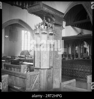 St. James' Church, Swimbridge, North Devon, Devon, 1940-1962. Detail einer mit Blei gesäumten Renaissance-Schrift mit Holzverkleidung, die einer Kanzel ähnelt. Die Schriftart hat drei Ebenen, von denen jede getäfelt ist. Die untere Ebene verfügt über einfache Tafeln, während die mittlere Ebene verzierte Tafeln hat, von denen einige Scharniere offen sind, um die Schriftart nach oben freizulegen, aber im Bild sind sie geschlossen. Die oberen Einsätze sind ebenfalls einfarbig, aber mit Spitzen versehen. Darüber befindet sich eine offene Krone und ein großes rechteckiges Vordach. Im Hintergrund befindet sich eine Chorwand, die die Kirche überquert und 1880 restauriert wurde. Darüber befindet sich ein Stockfoto