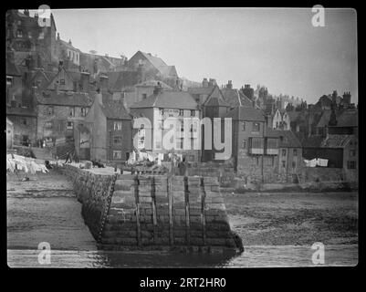 Whitby, Scarborough, North Yorkshire, 1925-1935.. Ein Blick auf den Tate Hill Pier in Whitby mit Häusern jenseits des Hafens auf Tate Hill und Church Street. Stockfoto
