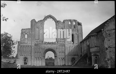 Priory of St Mary, St Peter und St Paul, Castle Acre, King's Lynn und West Norfolk, 1940-1949. Blick auf die Westfassade von Castle Acre Priory, von außerhalb der Ruinen gesehen, und die Prior's Lodgings, ein Gebäude aus dem 12. Jahrhundert, das im 15. Und 16. Jahrhundert umgebaut wurde und rechts von der Westfassade steht. Es gibt Steintreppen, die in das obere Stockwerk der Unterkünfte führen, die nicht mehr auf dem Gelände sind. Die gesamte Westfront ist in der Bildmitte zu sehen. Die Stätte wird von Engish Heritage gepflegt. Stockfoto