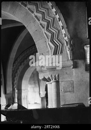 St John's Church, Elkstone, Cotswold, Gloucestershire, 1920-1940. Ein Detail mit einem Drachenkopf und Chevrons, die auf dem Chorbogen der St John's Church geschnitzt sind. Stockfoto