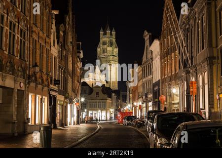 BRÜGGE, BELGIEN - 19. FEBRUAR 2016: Blick auf die Steenstraat bei Nacht in Richtung St. Salvator's Cathedral. Geschäfte, Autos und die Unschärfe von Menschen können s sein Stockfoto