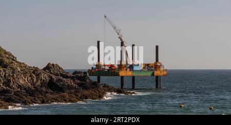 Polperro, Cornwall, England, Großbritannien. September 2023. Abhilfemaßnahmen, die von einer Aufbockplattform im Meer aus durchgeführt werden, um einen Außenposten mit Beton zu bedecken Stockfoto