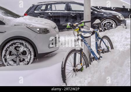 Winter in der Stadt, Autos und Fahrräder geparkt und geschneit Stockfoto