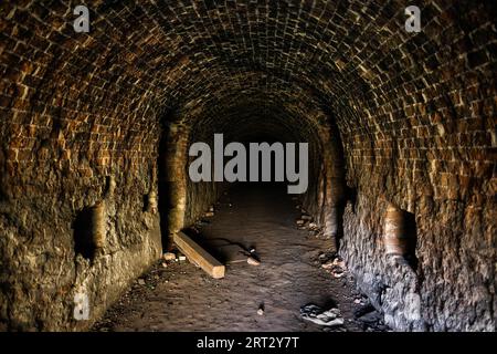 Grunge, gruseliger bogenförmiger Korridor in einem verlassenen Backsteingebäude, Stadterkundung, gespenstische Tunnel, unheimlicher Ort Stockfoto