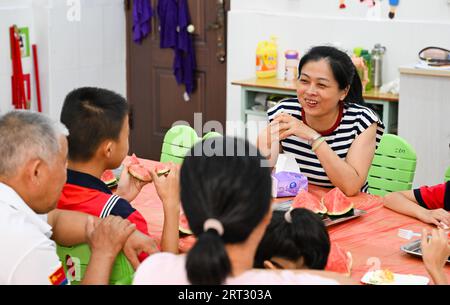 (230910) -- HAIKOU, 10. September 2023 (Xinhua) -- Fu Yaohui (R) spricht mit Schülern und ihren Familien an der Hainan (Haikou) Special School in Haikou, Südchinesische Provinz Hainan, 8. September 2023. Fu Yaohui ist Lehrer an der Sonderschule in Haikou. Seit 2004 engagiert sich Fu in Sonderpädagogik für Schüler mit geistiger Behinderung, um ihre Grundfertigkeiten zur Anpassung an das Leben zu entwickeln. Jeden Tag kommt Fu früh in die Schule und begleitet die Schüler mit Geduld und Ermutigung. „Ich möchte, dass meine Schüler selbstständig sind“, sagte sie. Um dieses Ziel zu erreichen, versucht sie es Stockfoto