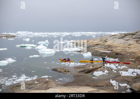 Ilulissat, Grönland, 1. Juli 2018: Gruppe von Menschen, die zwischen Eisbergen am Ilulissat Icefjord Kajak fahren. Ilulissat Icefjord wurde zur UNESCO erklärt Stockfoto