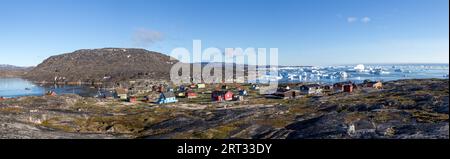 Rodebay, Grönland, 09. Juli 2018: Bunte Holzhäuser mit Eisbergen im Hintergrund. Rodebay, auch bekannt als Oqaatsut, ist eine Fischersiedlung Stockfoto