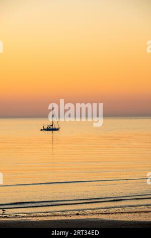 Eine Yacht vor Anker bei Sonnenuntergang an der Nordküste von Anglesey bei Cemaes in Wales Stockfoto