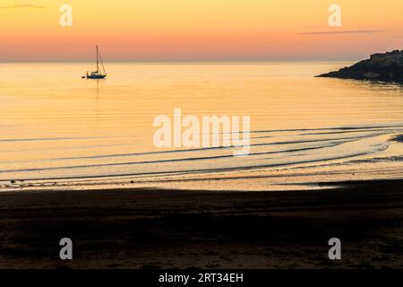 Eine Yacht vor Anker bei Sonnenuntergang an der Nordküste von Anglesey bei Cemaes in Wales Stockfoto