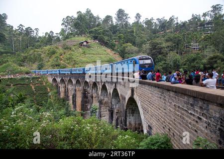 Demodara, Sri Lanka, 5. August 2018: Menschen neben einem blauen Zug, der die berühmte Nine Arch Bridge überquert Stockfoto