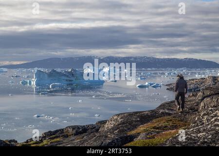 Rodebay, Grönland, 9. Juli 2018: A man is Walking and looking Ice ebergs. Rodebay, auch bekannt als Oqaatsut, ist eine Fischersiedlung nördlich von Stockfoto