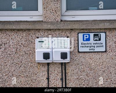 Zwei Evolt-Ladestationen für Elektrofahrzeuge (EV) mit Schildern an einer Kieselsteinmauer im Bernera Community Centre in den Äußeren Hebriden, Schottland, Stockfoto