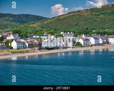 Strandhäuser und andere Gebäude am Hafen von Ullapool in Schottland, Großbritannien. Von der ankommenden Fähre von Stornoway an einem klaren, sonnigen Nachmittag genommen Stockfoto