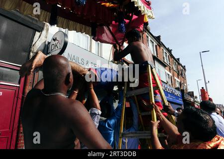 London, Großbritannien. September 2023. Tausende hinduistische Gläubige versammeln sich in Walthamstow im Osten Londons, um die jährliche Prozession des Sri Karphaha Vinayagar Temple Rathayatra zu feiern, bei der ein Wagen von Gläubigen in einem Zeichen der Einheit und des Glaubens gezogen wird. Einige Devotees entscheiden sich dafür, dass Haken durch ihren Rücken gepierct werden, die an Seilen befestigt sind, die andere Devotees halten, und ein Devotee auf der Prozession wird von ihren hinteren Haken auf eine Struktur auf einem Van gehisst, wo er für die Dauer des Tages gehängt wird. © Simon King/Alamy Live News Stockfoto