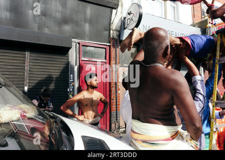 London, Großbritannien. September 2023. Tausende hinduistische Gläubige versammeln sich in Walthamstow im Osten Londons, um die jährliche Prozession des Sri Karphaha Vinayagar Temple Rathayatra zu feiern, bei der ein Wagen von Gläubigen in einem Zeichen der Einheit und des Glaubens gezogen wird. Einige Devotees entscheiden sich dafür, dass Haken durch ihren Rücken gepierct werden, die an Seilen befestigt sind, die andere Devotees halten, und ein Devotee auf der Prozession wird von ihren hinteren Haken auf eine Struktur auf einem Van gehisst, wo er für die Dauer des Tages gehängt wird. © Simon King/Alamy Live News Stockfoto