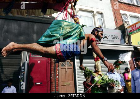 London, Großbritannien. September 2023. Tausende hinduistische Gläubige versammeln sich in Walthamstow im Osten Londons, um die jährliche Prozession des Sri Karphaha Vinayagar Temple Rathayatra zu feiern, bei der ein Wagen von Gläubigen in einem Zeichen der Einheit und des Glaubens gezogen wird. Einige Devotees entscheiden sich dafür, dass Haken durch ihren Rücken gepierct werden, die an Seilen befestigt sind, die andere Devotees halten, und ein Devotee auf der Prozession wird von ihren hinteren Haken auf eine Struktur auf einem Van gehisst, wo er für die Dauer des Tages gehängt wird. © Simon King/Alamy Live News Stockfoto