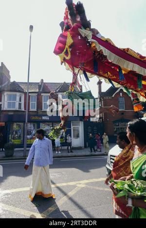 London, Großbritannien. September 2023. Tausende hinduistische Gläubige versammeln sich in Walthamstow im Osten Londons, um die jährliche Prozession des Sri Karphaha Vinayagar Temple Rathayatra zu feiern, bei der ein Wagen von Gläubigen in einem Zeichen der Einheit und des Glaubens gezogen wird. Einige Devotees entscheiden sich dafür, dass Haken durch ihren Rücken gepierct werden, die an Seilen befestigt sind, die andere Devotees halten, und ein Devotee auf der Prozession wird von ihren hinteren Haken auf eine Struktur auf einem Van gehisst, wo er für die Dauer des Tages gehängt wird. © Simon King/Alamy Live News Stockfoto