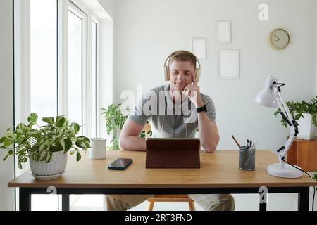 Lächelnder Mann, der Kopfhörer trägt, wenn er in der Pause Musik hört Stockfoto