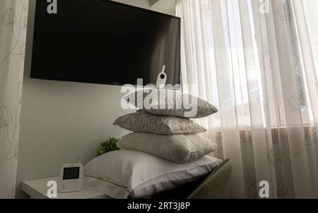 Video-Nanny im Schlafzimmer auf einem Haufen Kissen Stockfoto